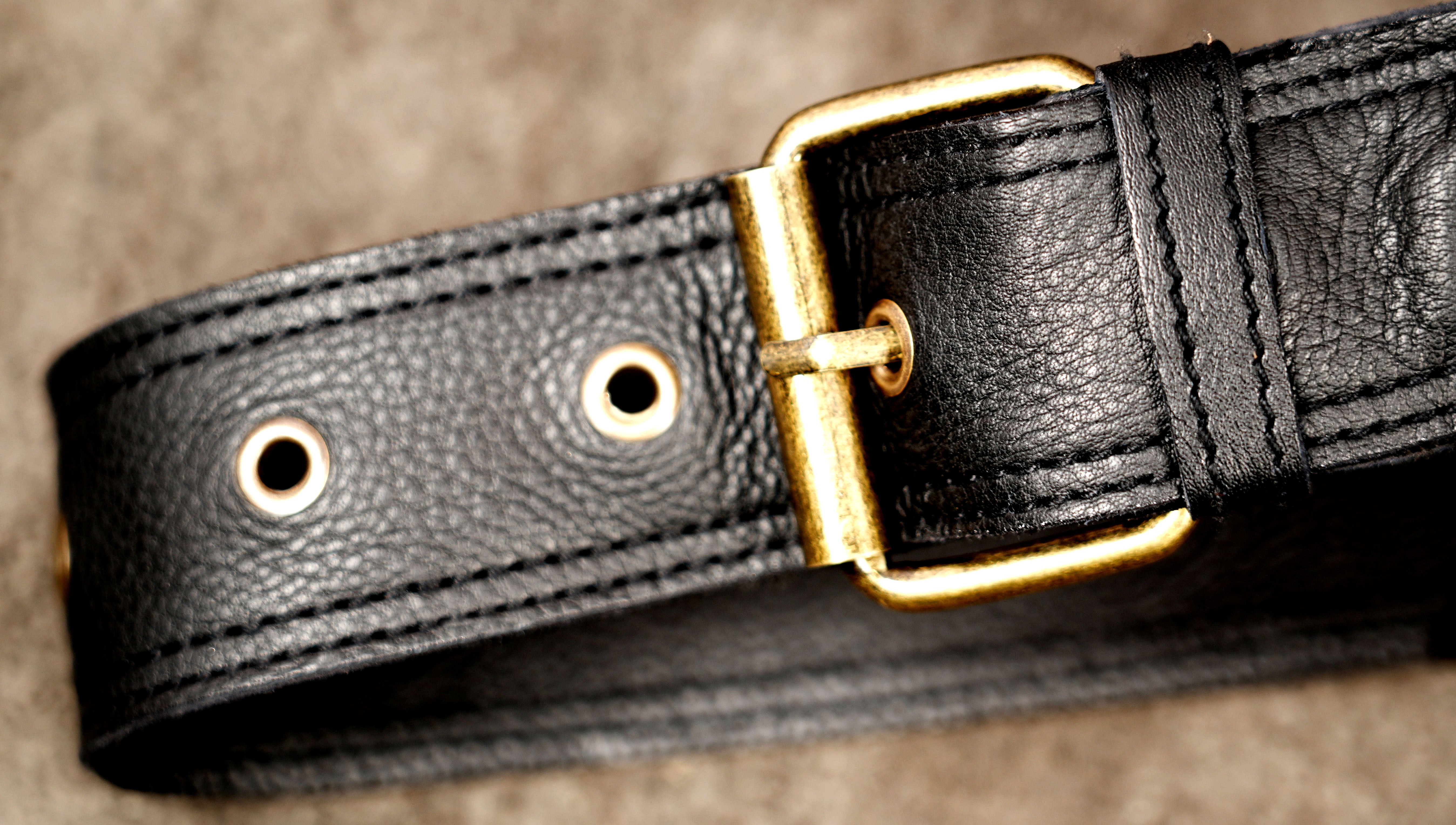 Black leather utility belt bag with decorative flower patterns and brass-tone hardware.