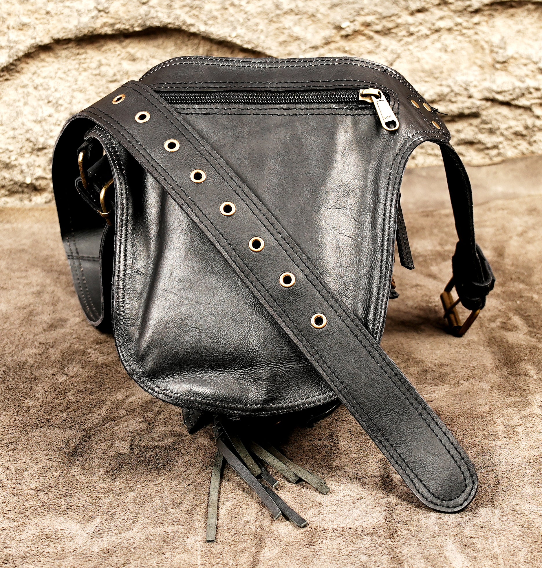 Multifunctional leather hip purse with a secure leg strap attachment and brass hardware.