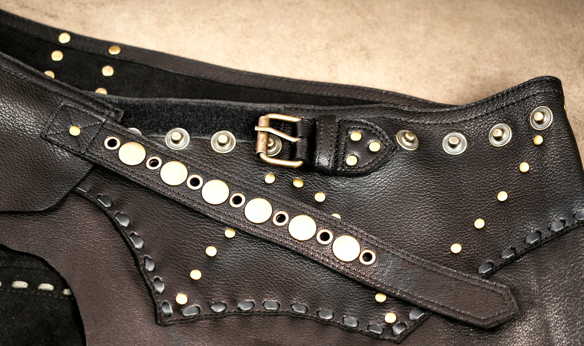 Unisex-inspired leather utility skirt with studded detailing and an asymmetrical hem