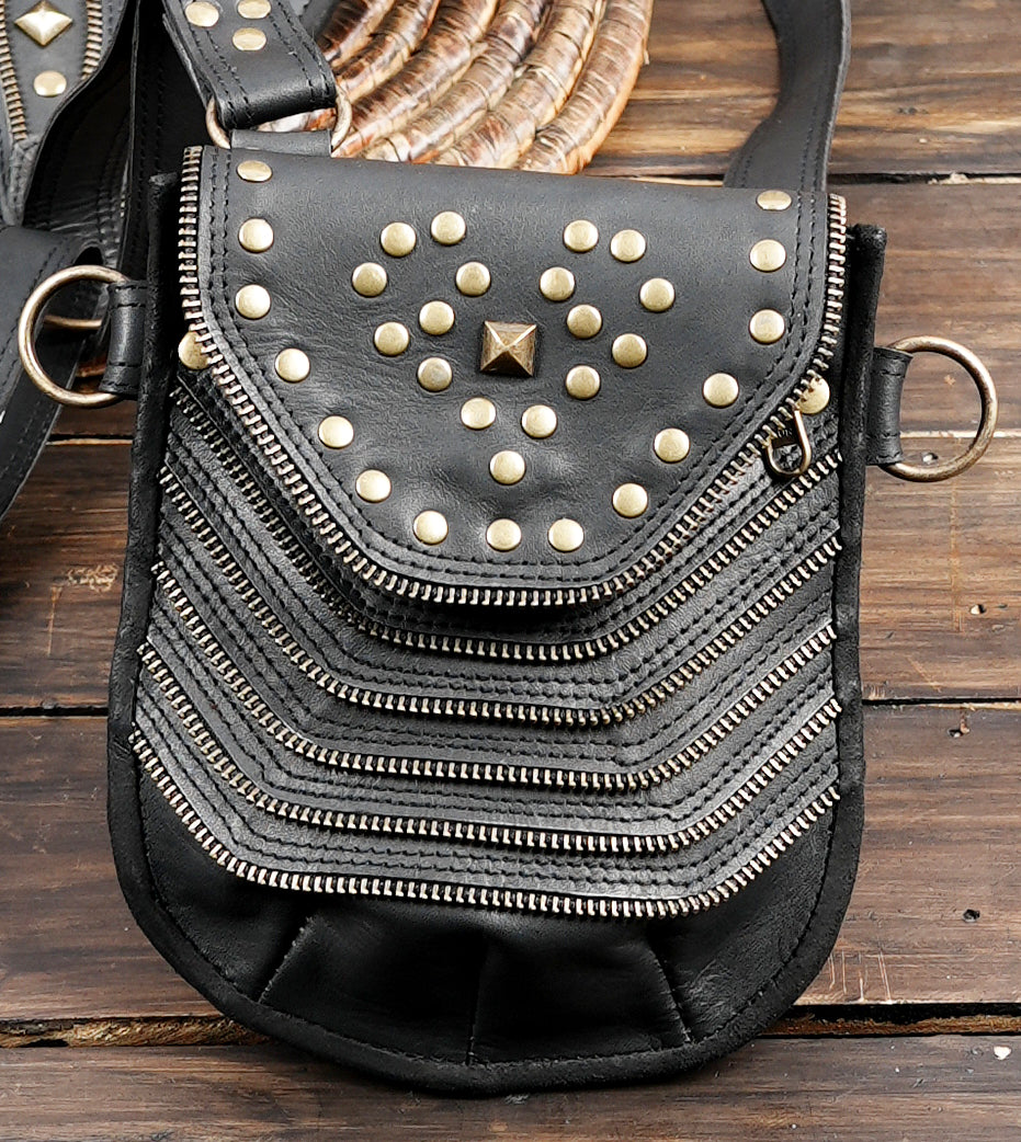 Unisex black leather harness bag with two front hip pouches and gold tone studs
 
