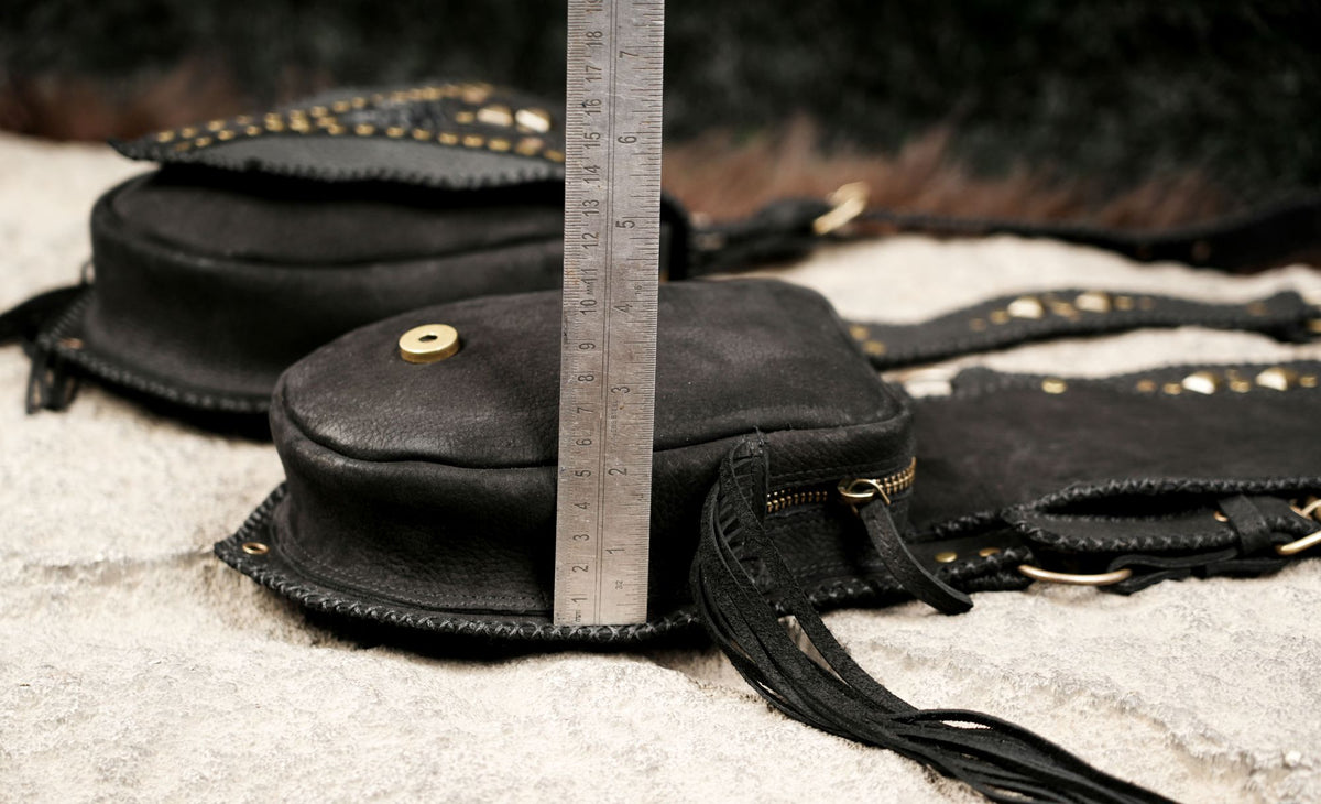 Alternative fashion leather harness with matching leg pouches, decorative studs, and black leather fringe.