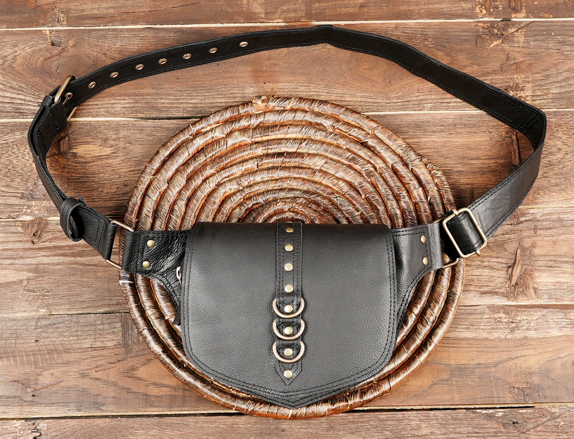 Black leather fanny pack resting on a rustic wooden table