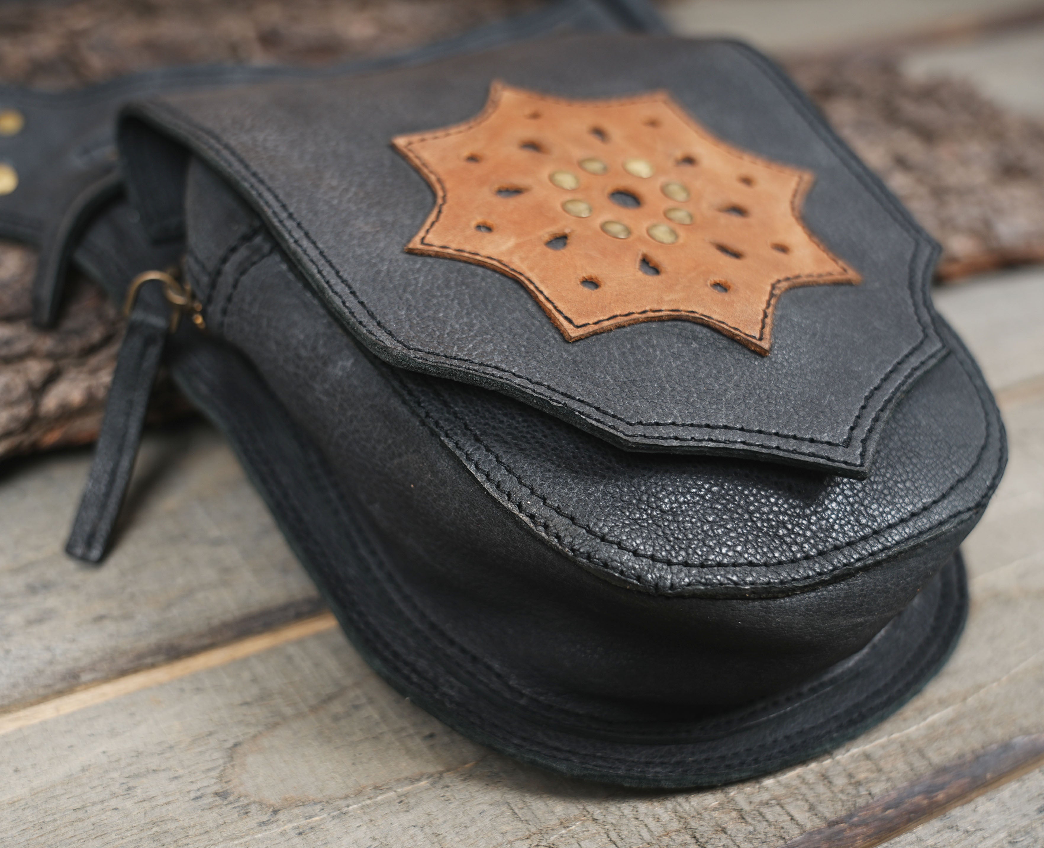 Black leather holster pouch with star design, flat lay on wood background