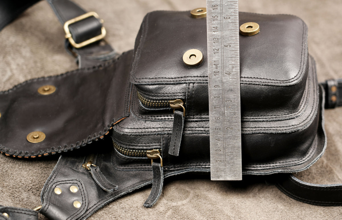 Black leather leg bag with brass hardware, close up view