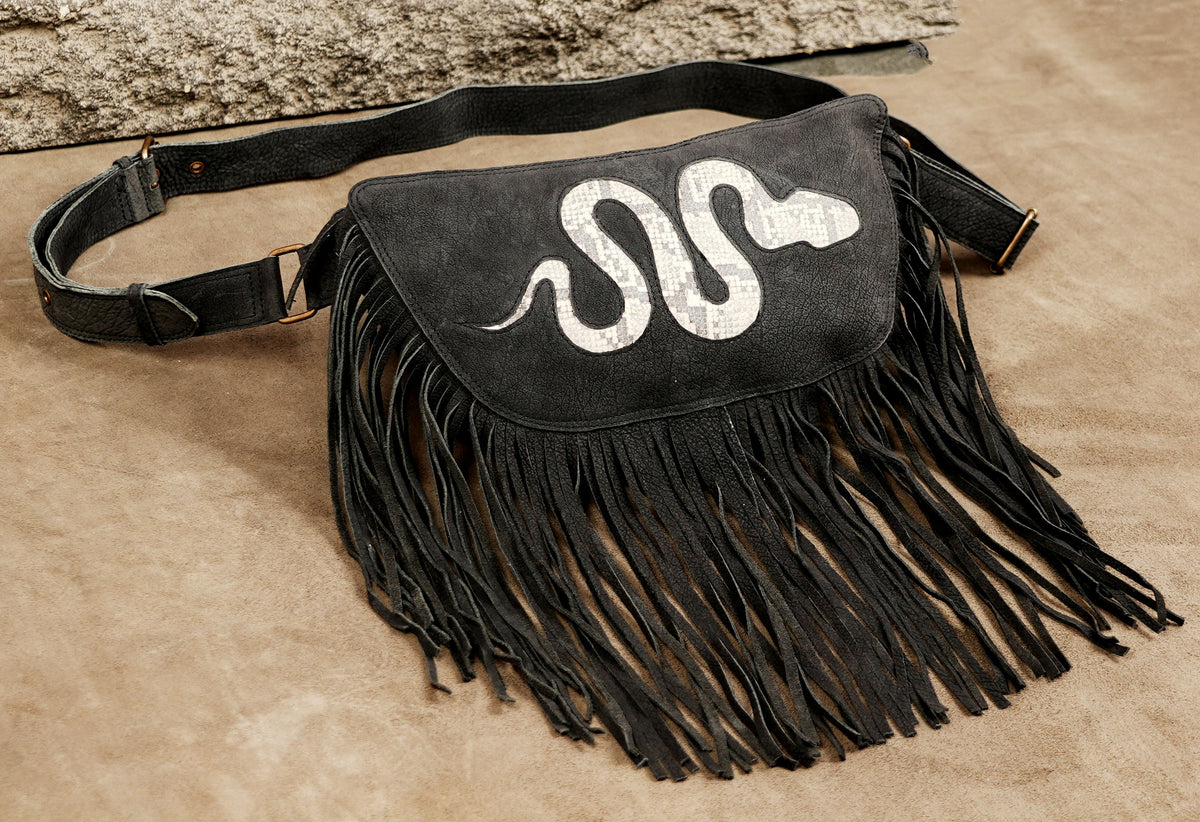 Handmade black leather waist pack with long fringe and white snake decoration.
