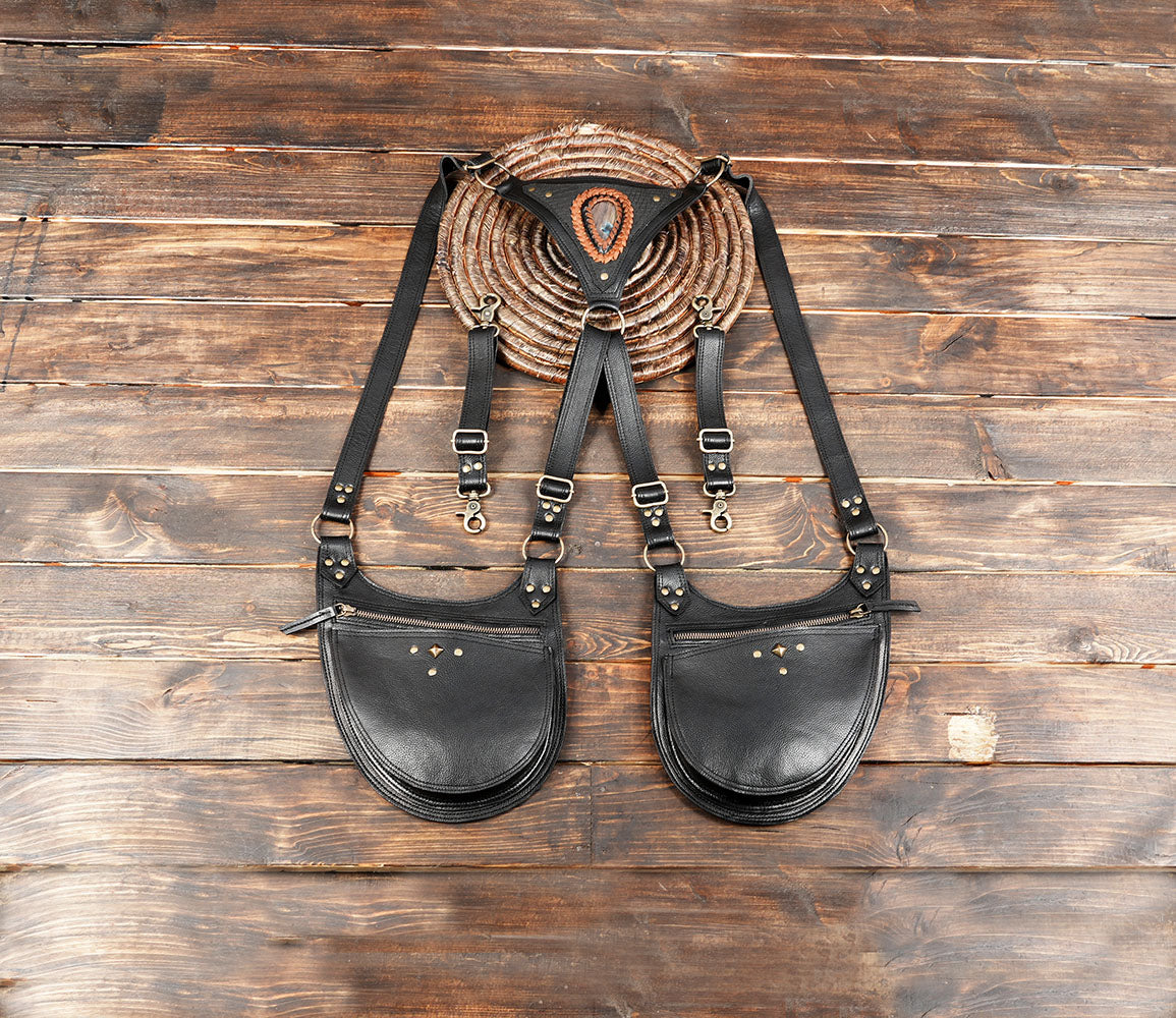 Black leather dual pouch utility harness with antique brass studs and adjustable shoulder straps for festivals.
