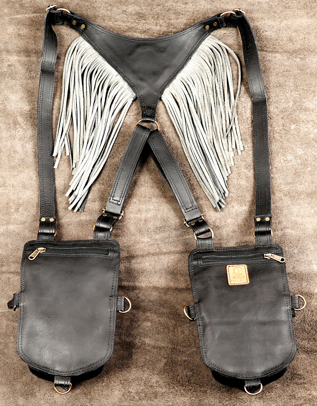 Dual-pocket leather shoulder holster with brass hardware, buckle adjustments, and fringed back yoke.