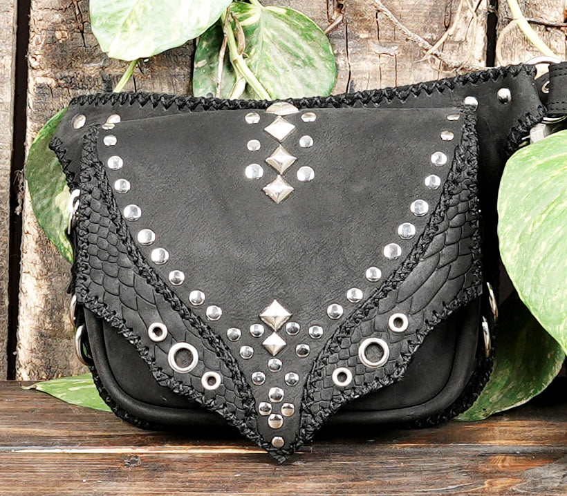 "Artisan leather belt bag featuring rivets and a shaped flap"