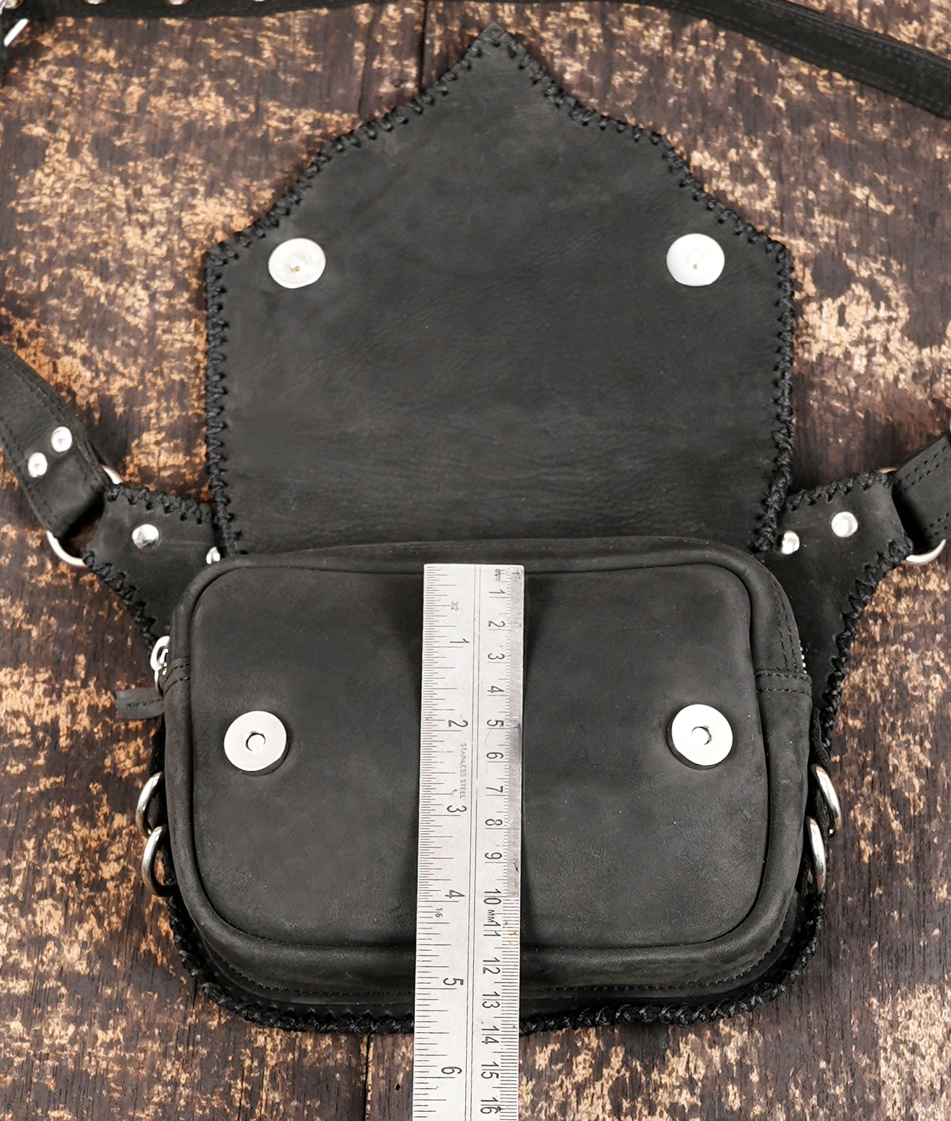 "Adjustable leather hip bag with studded design and flap closure"