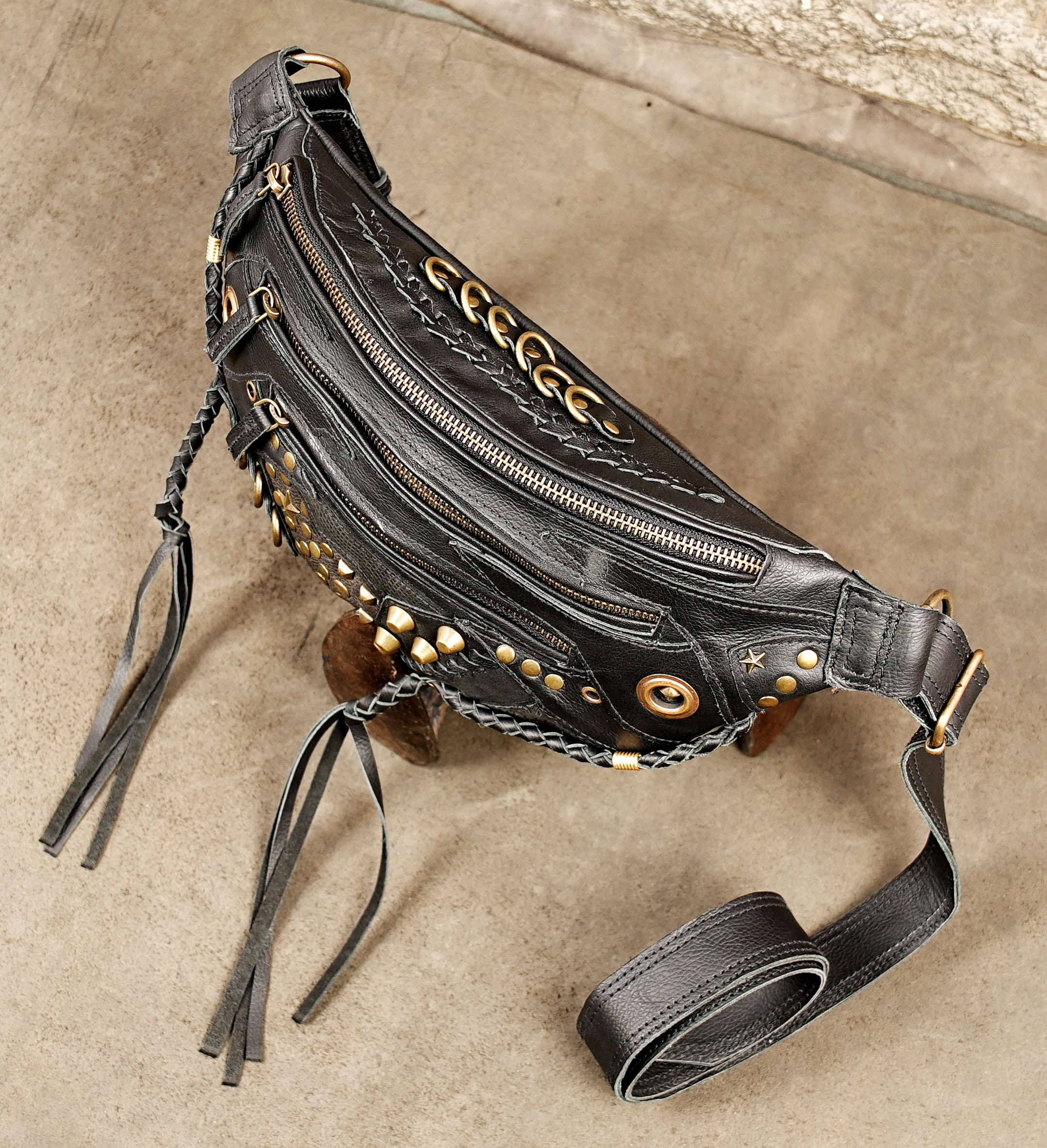 Cyberpunk-inspired black leather utility hip bag with multiple zippered compartments and brass studs.