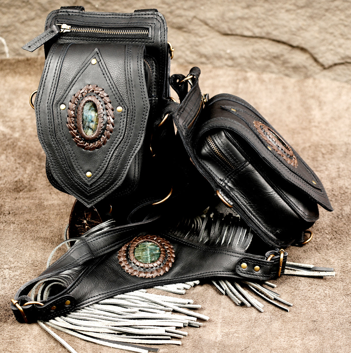 Overhead view of black leather harness pouch bag with fringe back panel and detachable utility clips.