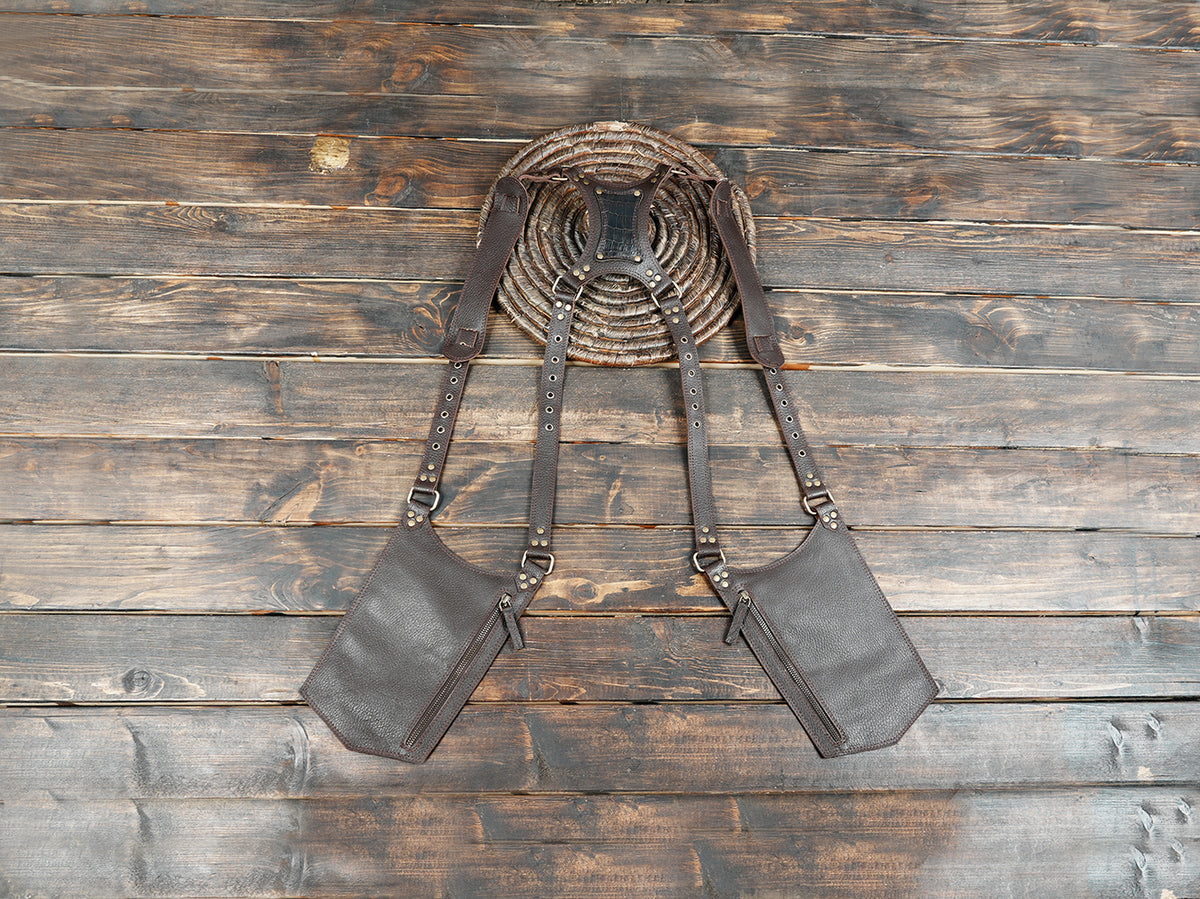 Brown leather double thigh holster harness with adjustable straps and antique brass studs.