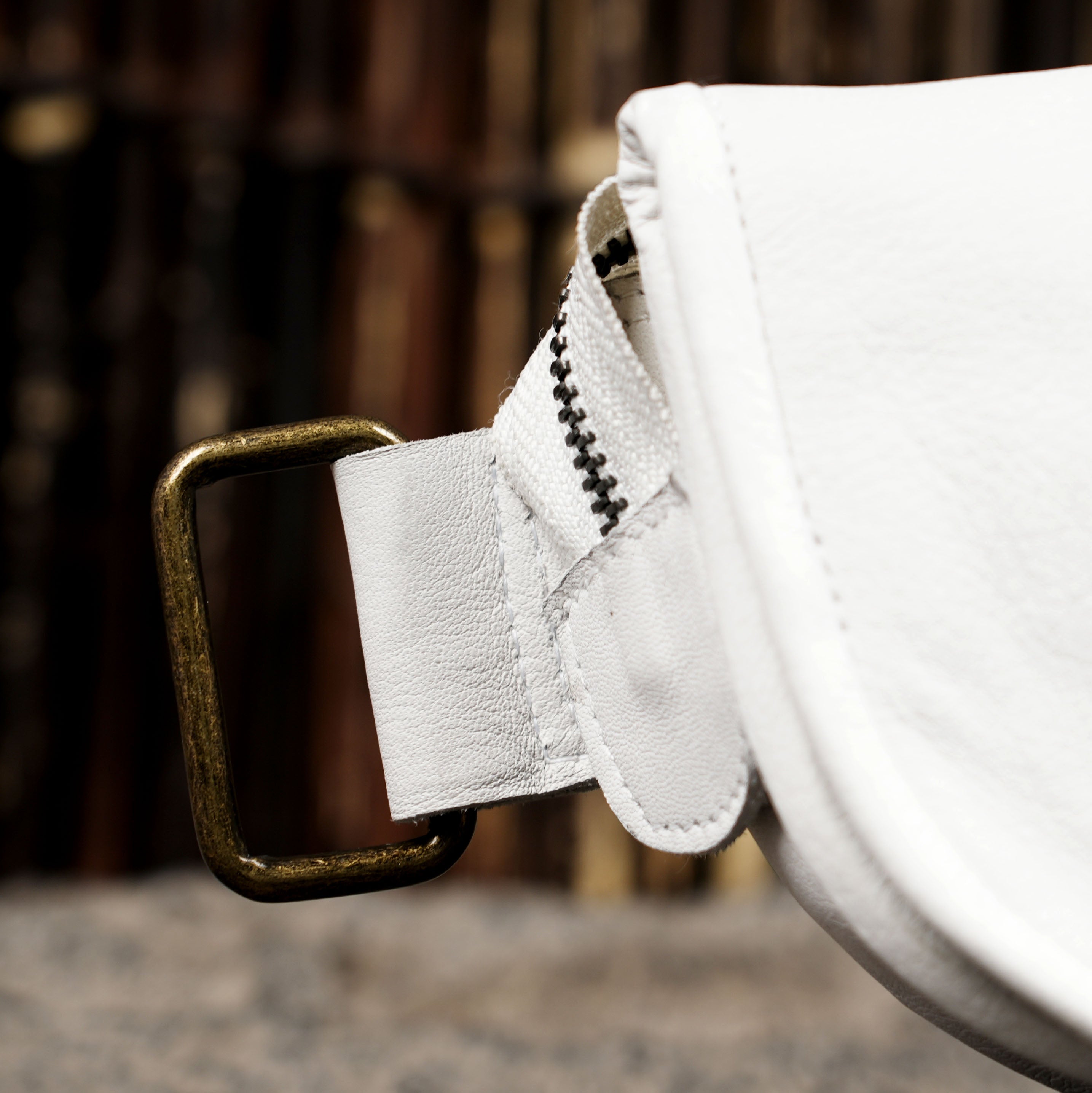 Genuine white leather hip bag styled on dark stone background