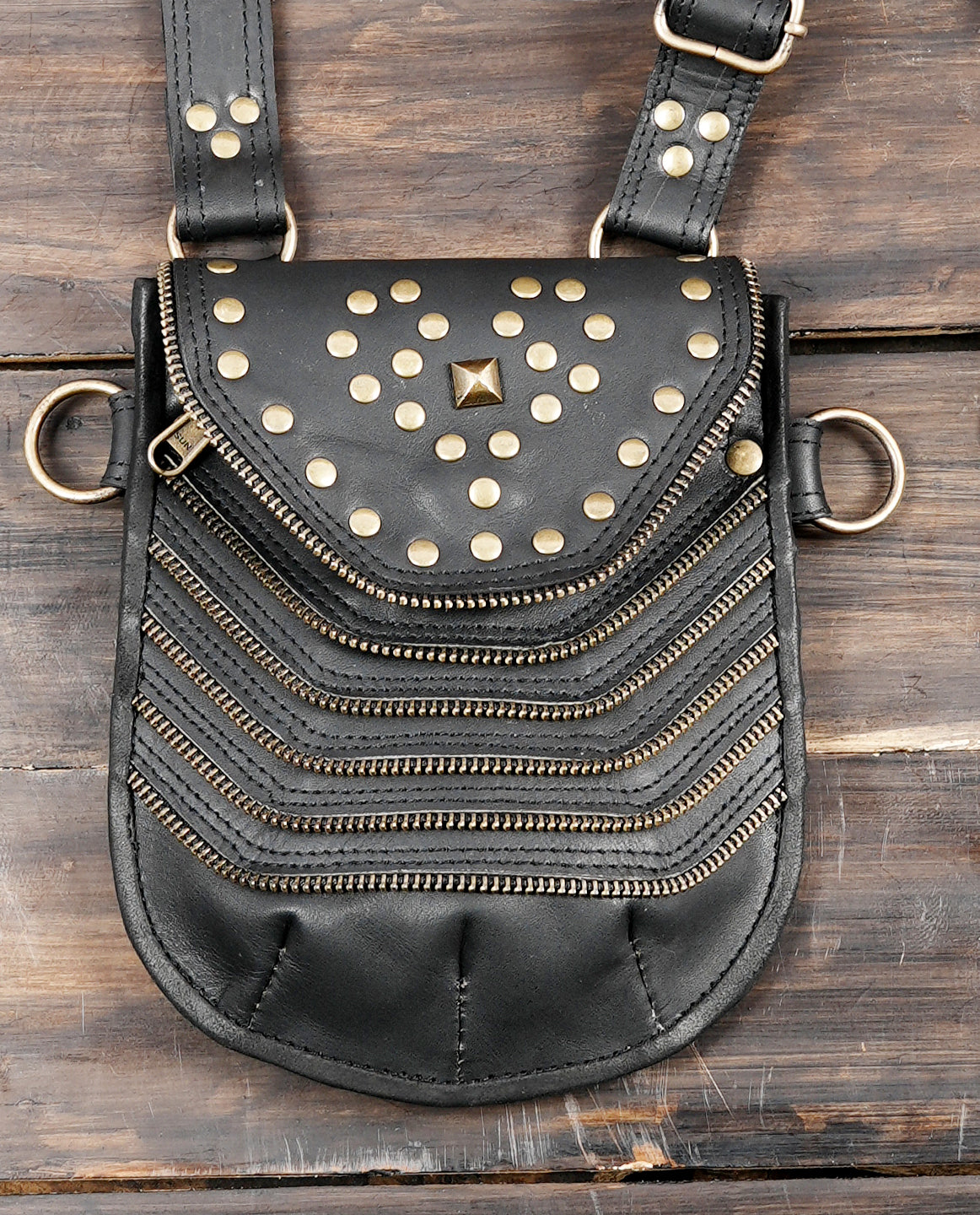 Black leather crossbody style harness with two hip pouches and metal ring attachments
