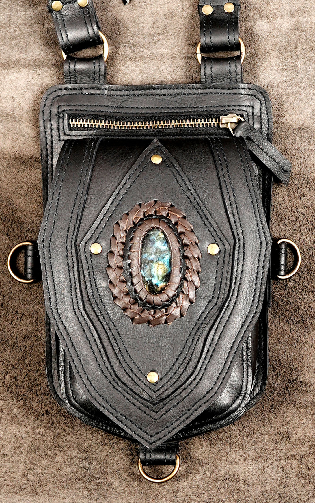 Front view of twin-pocket black leather festival harness bag with gemstone inlay and flowing fringe.