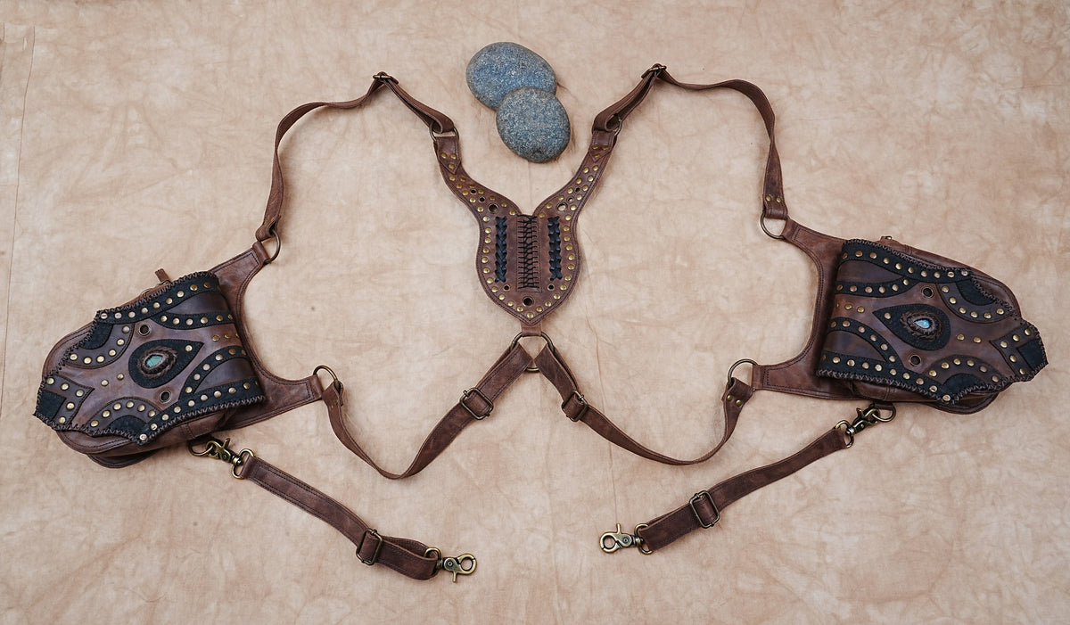 Brown leather double holster style bag with ornate flaps and decorative brass-tone rivets.