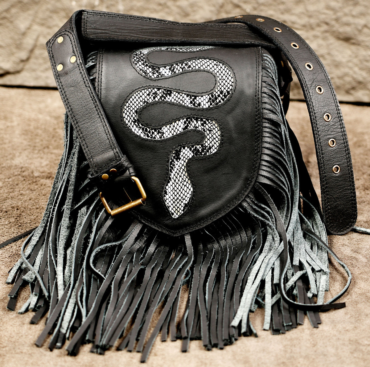 Black leather shoulder bag with a large fringe skirt, a black strap, and a silver snakeskin-patterned snake graphic on the front.