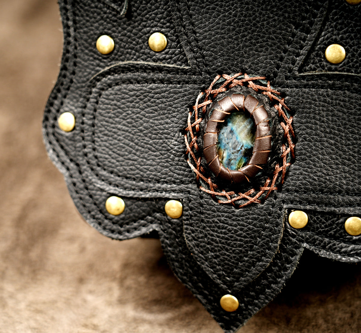 Handmade leather festival bag with gemstone accents and adjustable shoulder straps
