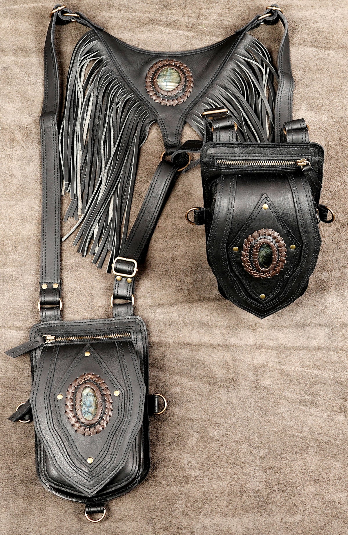 Handcrafted black leather harness bag featuring long back tassels, adjustable straps, and decorative stone centerpiece inlays.