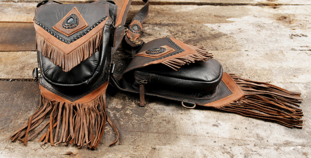 Black leather hip holster bags with brown panels and blue green gemstone details
