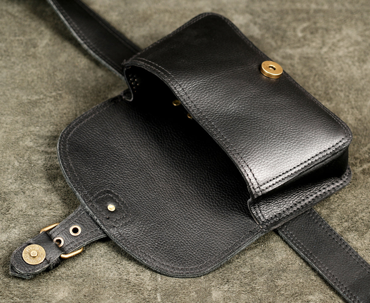 Black textured leather hip bag with brass buckle on front flap