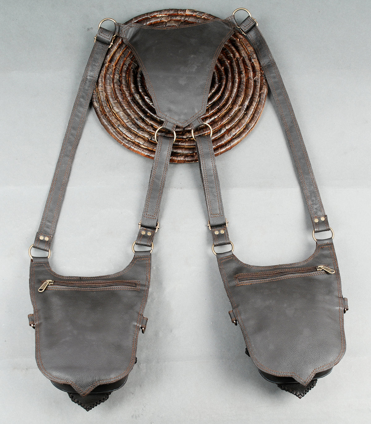 Alternative fashion leather harness with twin grey pouches braided borders and metallic fittings.