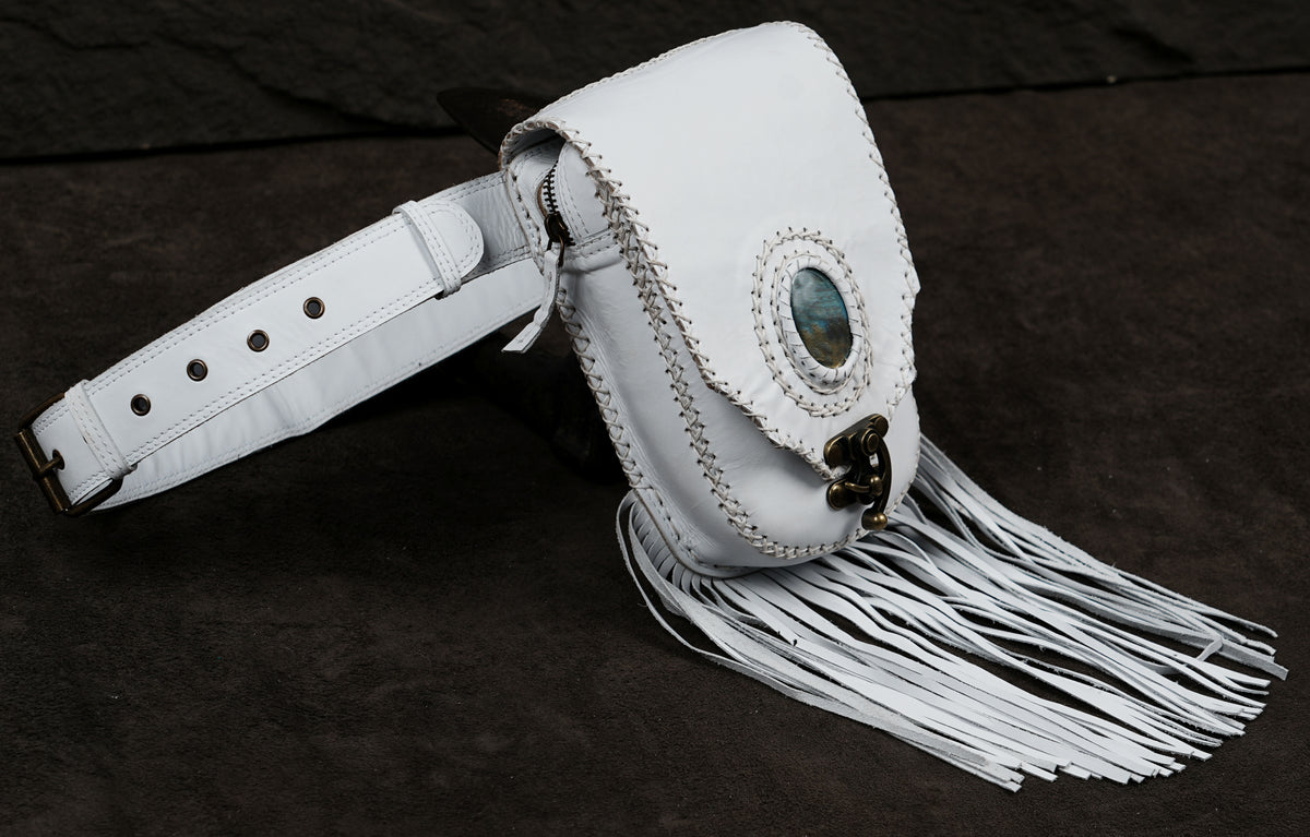 A white leather fringe pouch bag with a decorative oval inlay and brass-tone hardware.