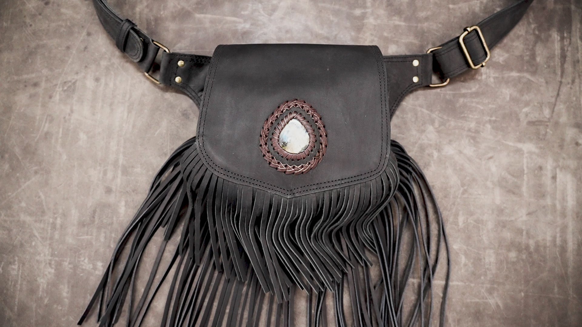 Boho chic black fringe waist bag with gemstone accent laid flat