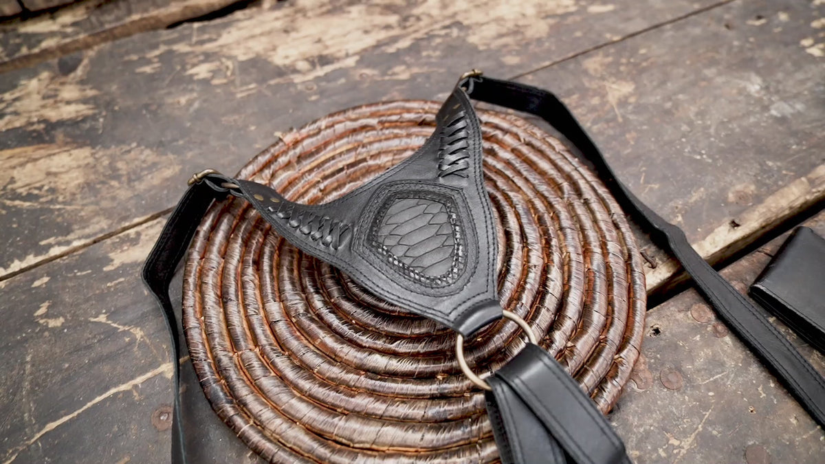 Handmade black leather shoulder holster with decorative flap details and antique brass hardware