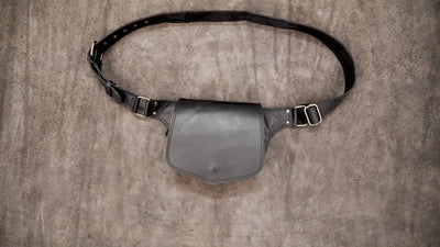 Handcrafted black leather bum bag showing adjustable brass buckle detail.