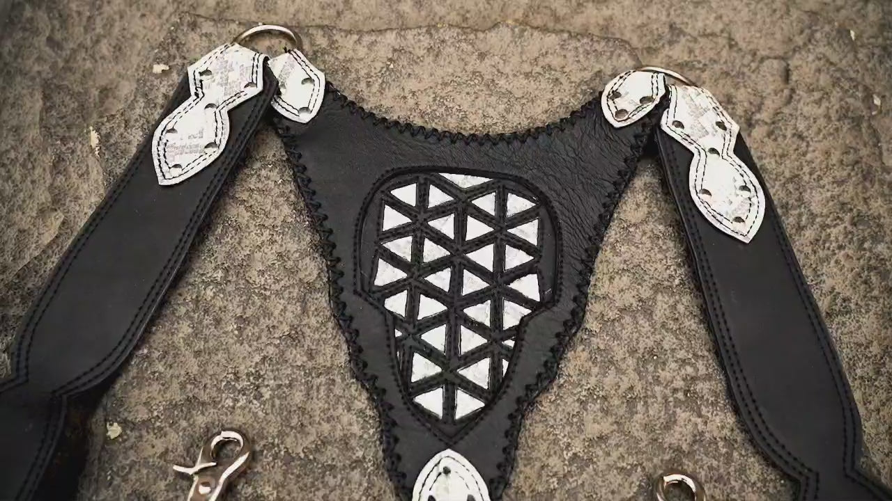 Leather body harness bag with adjustable straps, front view on stone background