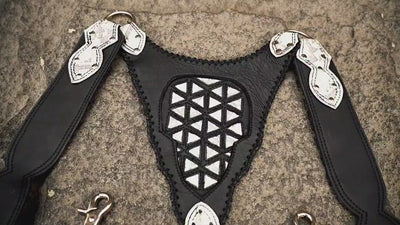 Leather body harness bag with adjustable straps, front view on stone background