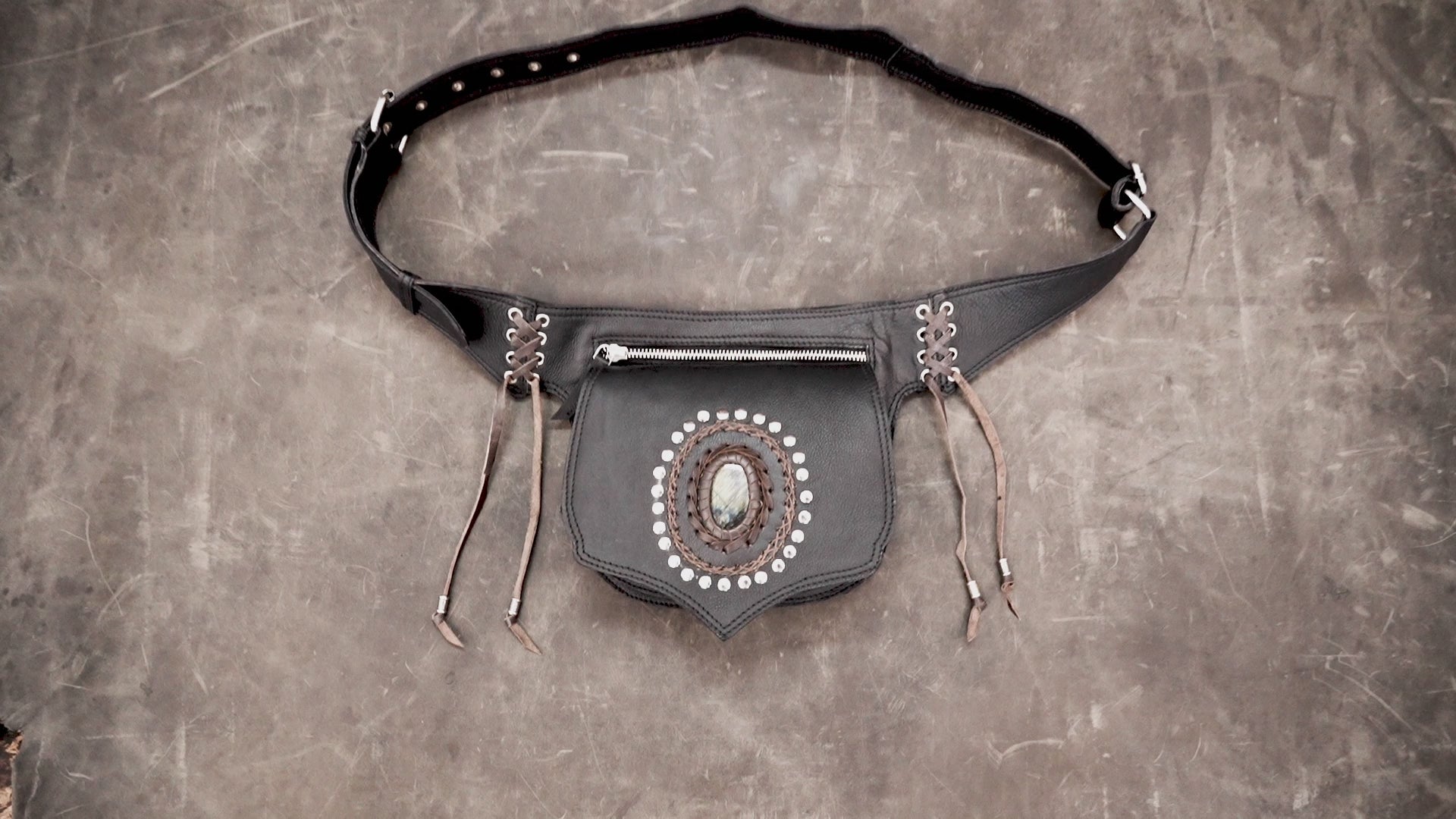 Boho style black leather fanny pack featuring silver studs and a raw stone crystal.